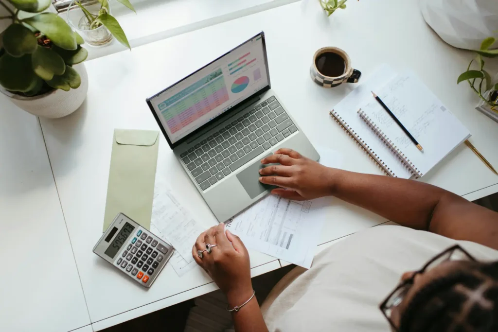 Pessoa analisando dados de mercado em uma reunião sobre técnicas de negociação salarial baseadas em dados de mercado, com laptop, anotações e calculadora na mesa.