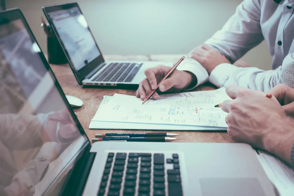 Equipe de profissionais analisando estratégias de análise preditiva usando inteligência artificial em ambiente de escritório com laptops e documentos.