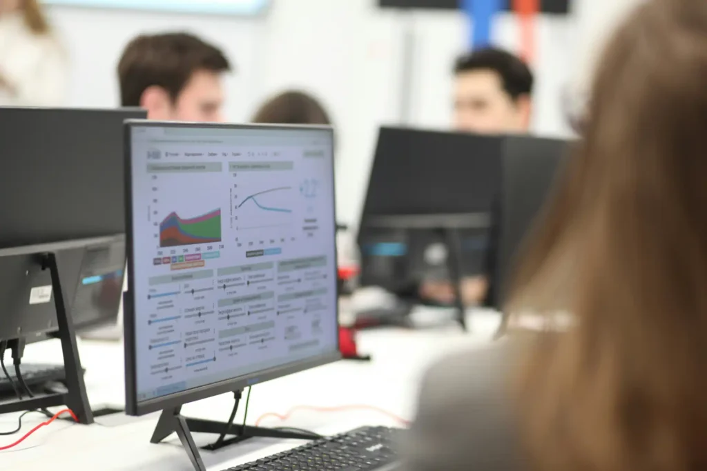Pessoa analisando gráficos de concorrência em computador durante reunião de negócios, foco em análise de mercado e estratégias competitivas