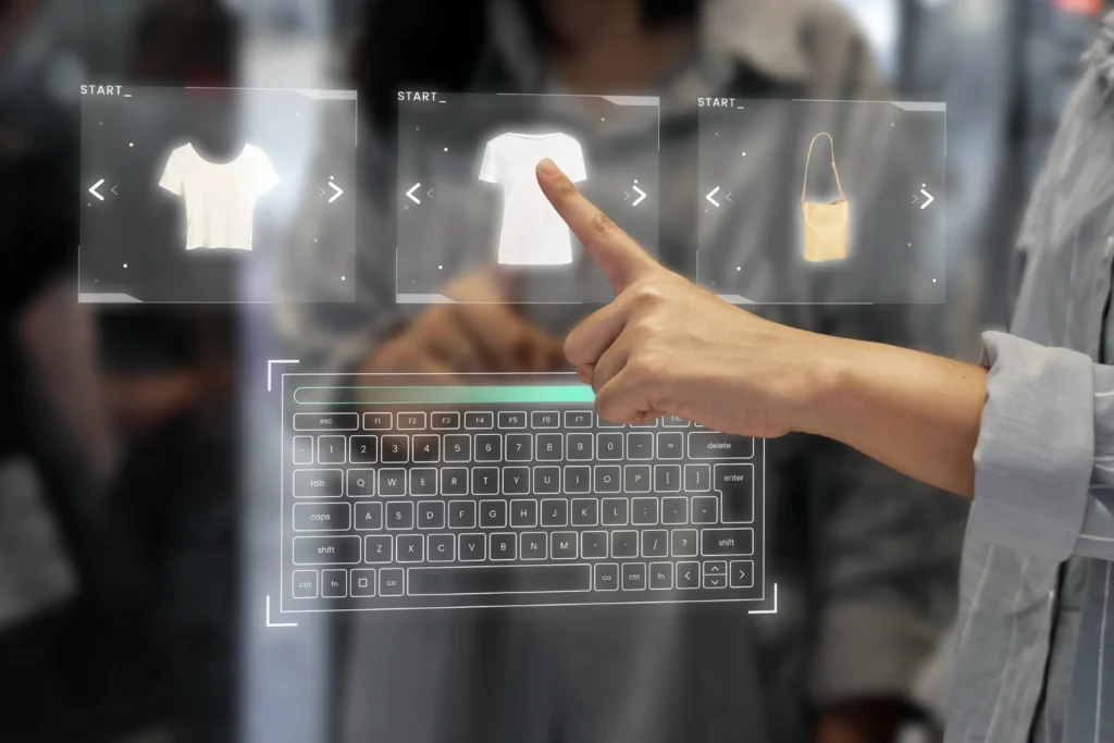 Pessoa usando o teclado em frente a uma interface holográfica com ícones de roupas, sugerindo tecnologia para e-commerce e Como Criar um Site de Compras Coletivas do Zero