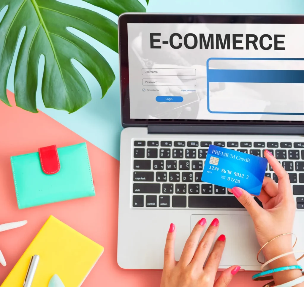Mesa de trabalho com laptop mostrando e-commerce, cartão de crédito sendo usado e acessórios como carteira e folhas coloridas, ideal para Dicas de SEO para Sites de E-commerce Iniciantes.
